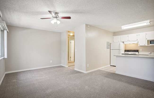 an empty living room and kitchen with a ceiling fan