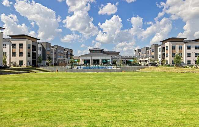 A large grassy field in front of apartment buildings.