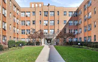 A long brick building with a walkway in front.