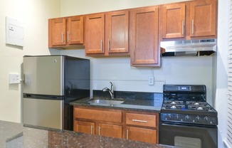 kitchen with wood cabinetry, gas stove, and granite countertops at dupont apartments in washington dc