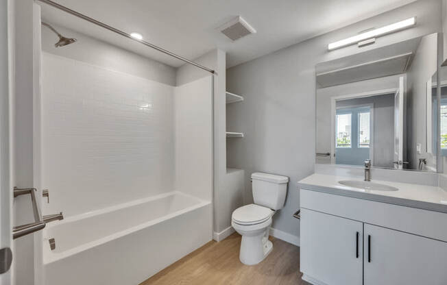A white bathroom with a toilet, sink, and bathtub.
