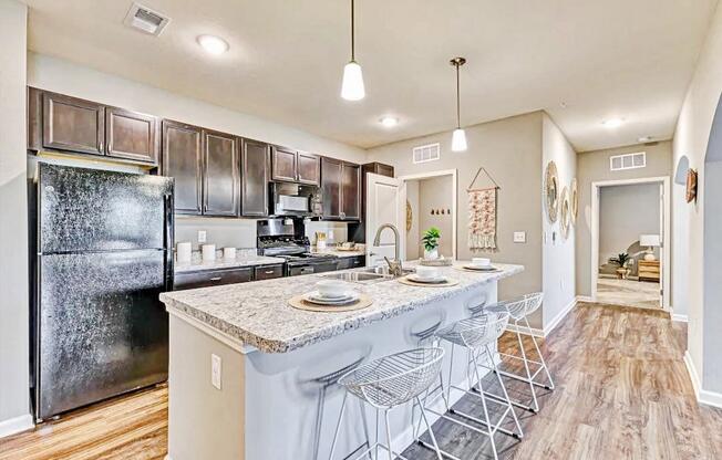 an open kitchen with a bar with stools and a refrigerator at the flats at sundown luxury apartments in north port florida