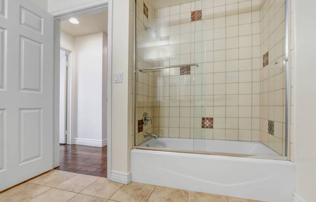 a bathroom with white tile and a white bathtub