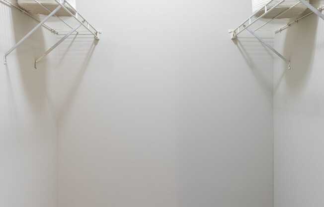 an empty room with two hanging racks on the wall and a carpeted floor