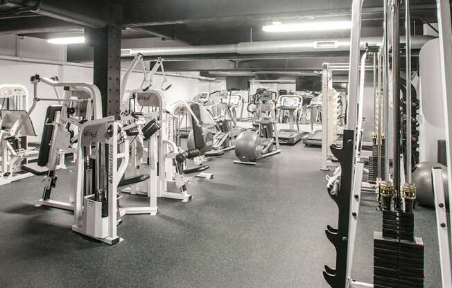 A gym with a variety of equipment including treadmills, weights, and exercise machines.