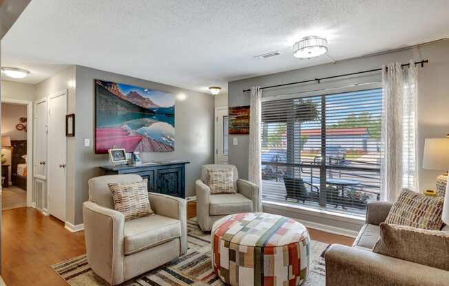 a living room with chairs and a table and a large window