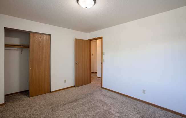 a bedroom with carpet and a door to a closet. Fargo, ND Southview Village Apartments