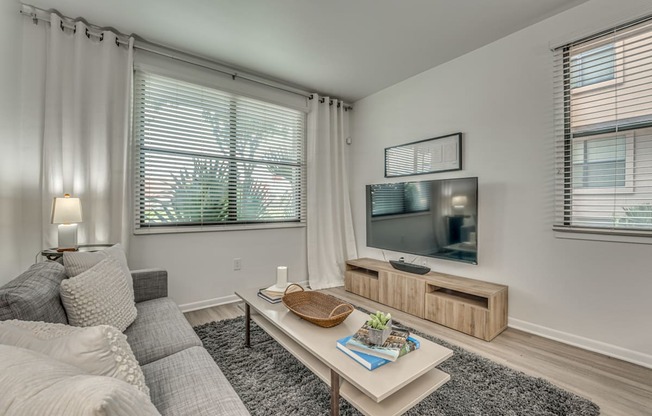A living room with a grey couch, a white coffee table, and a flat screen TV.