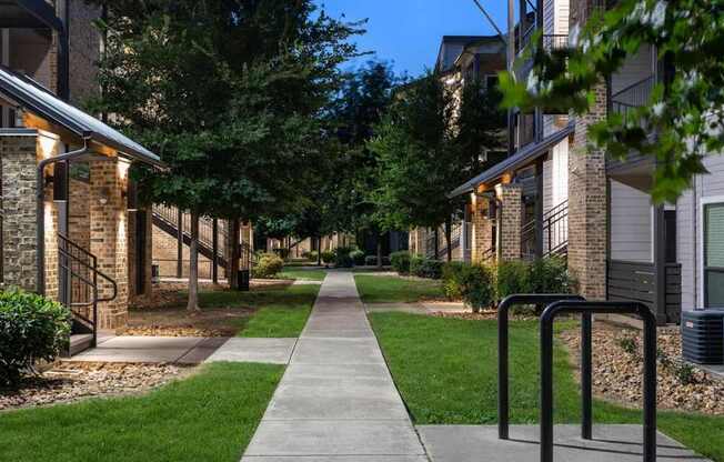 A long walkway with a metal railing on the right side and apartment buildings on both sides.