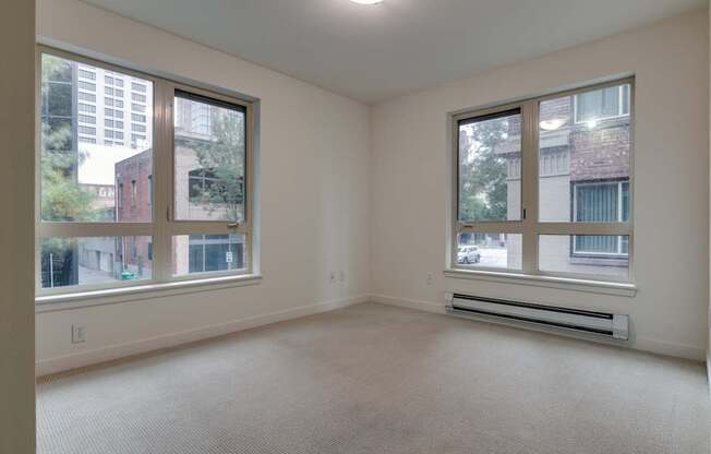 A spacious room with two windows overlooking a cityscape.