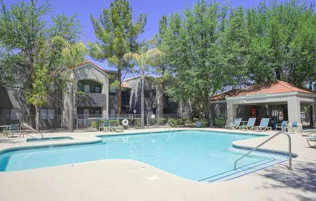 A swimming pool surrounded by trees and a building in the background.