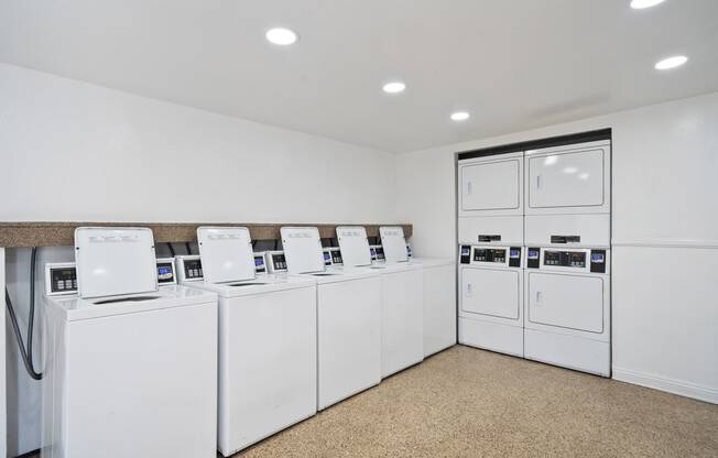 a laundry room with white washers and dryers