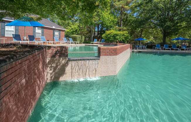 A swimming pool surrounded by a brick wall and trees.
