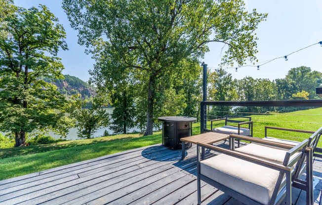 A wooden deck with a bench and a table is surrounded by trees.