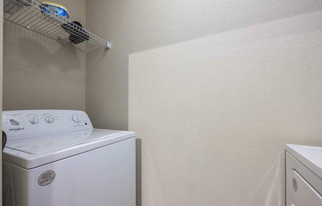 A white dryer is on the left in a small laundry room.