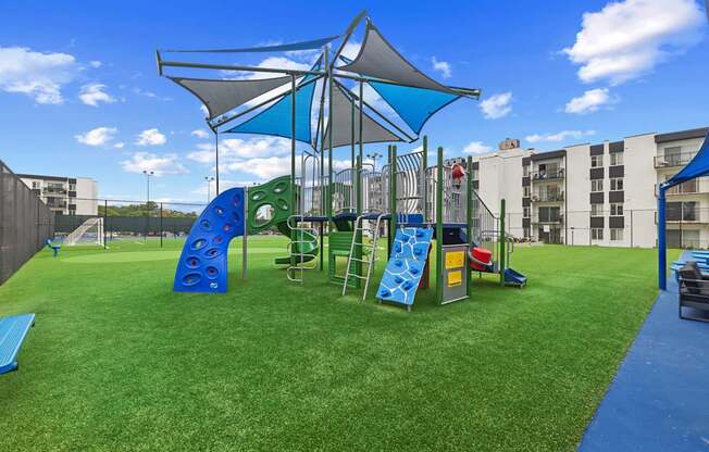 A playground with a blue slide and rockwalland a green slide.