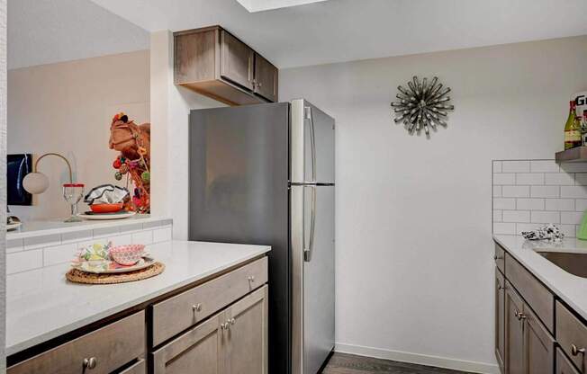 A kitchen with a refrigerator, countertop, and cabinets.