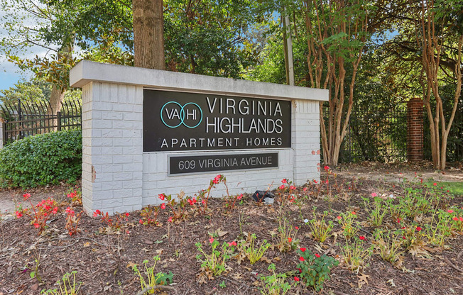A sign for Virginia Highlands Apartment Homes stands in front of a tree.