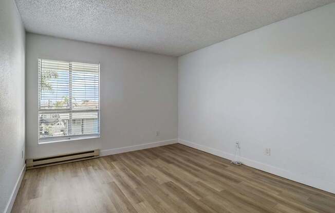 A room with a window and wooden flooring.