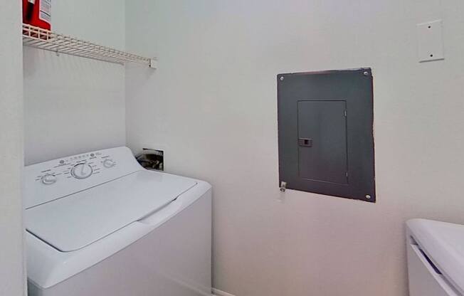 A white washing machine sits in a laundry room.