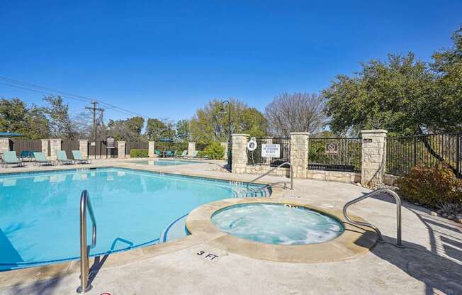 Our sparkling pool with a hot tub and poolside seating at On the Green apartments in Austin, TX