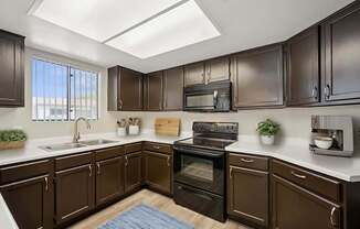 A kitchen with brown cabinets and a black stove top oven.