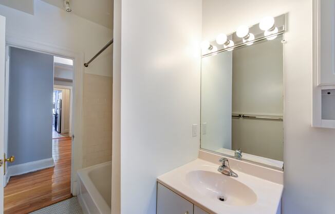 bathroom with vanity, mirror, tub and view of hallway at the shawmut apartments in adams morgan washington dc