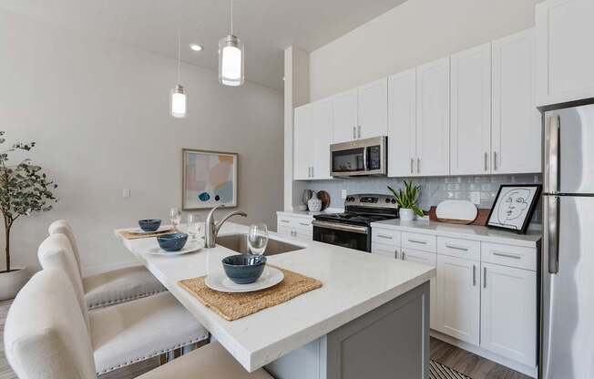 an open kitchen and dining area with white cabinets and stainless steel appliances
