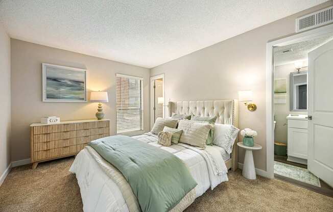 A bedroom with a bed, nightstand, and a painting on the wall.