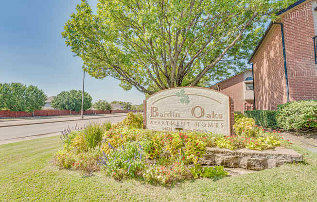 A sign for Bardin Oaks Apartment Homes is surrounded by greenery.