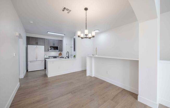 an open kitchen and living room with white walls and wood floors