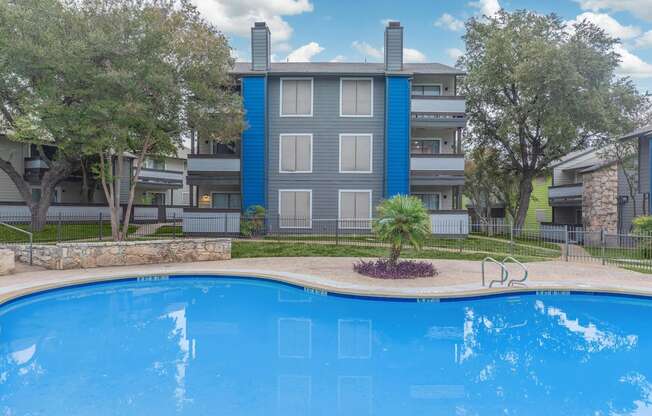 a large swimming pool with an apartment building in the background