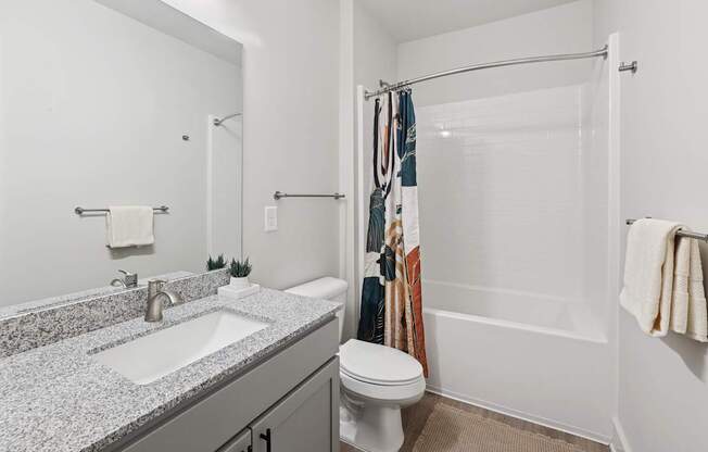 A bathroom with a toilet, sink, and shower.