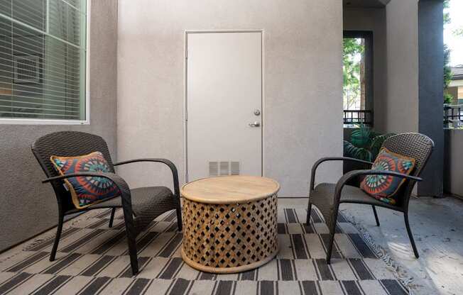 Two chairs and a table are on a patio.