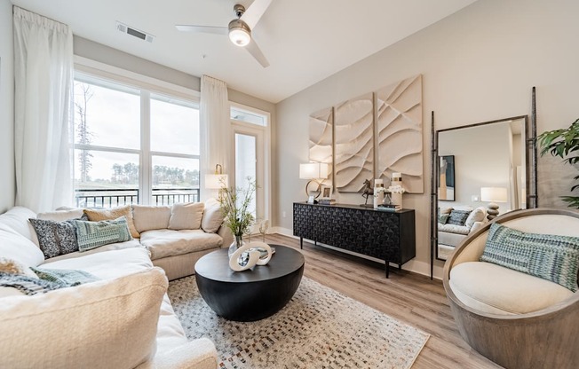 A living room with a white couch, a black coffee table, and a large mirror.
