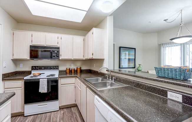 A kitchen with a stove, oven, microwave, and sink.