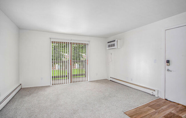 an empty living room with a slider to a private balcony