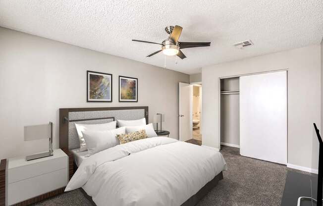 A bedroom with a large bed, a ceiling fan, and two pictures on the wall.
