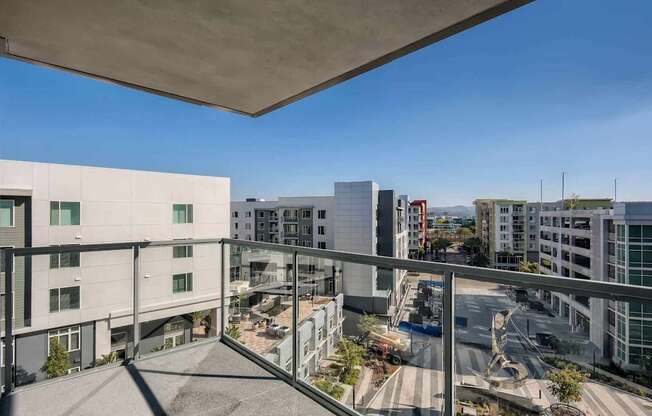 A view from a balcony overlooking a parking lot and buildings.