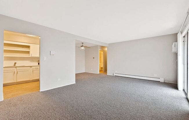 the living room and kitchen of an apartment with a carpeted floor