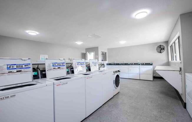 A laundry room with washing machines and a fan on the wall.