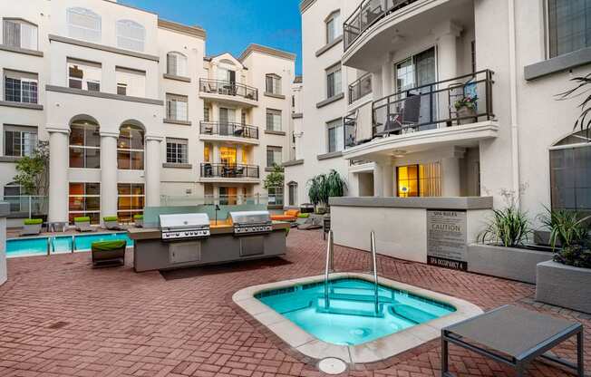 Miracle Mile, Los Angeles, CA Apartments - The Preston Miracle Mile - Resort-Inspired Pool Area With A Sparkling Pool, Hot Tub, Lounge Chairs, Umbrellas, And Two BBQ Grilling Stations
