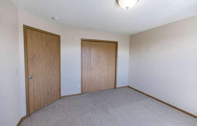 Room with a carpeted floor and two doors at Sunset Ridge Apartments in Bismarck