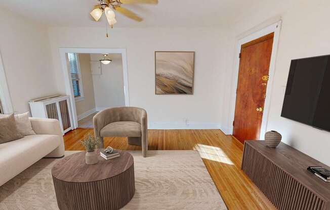 A living room with a white couch, a brown armchair, a coffee table, and a flat-screen TV.