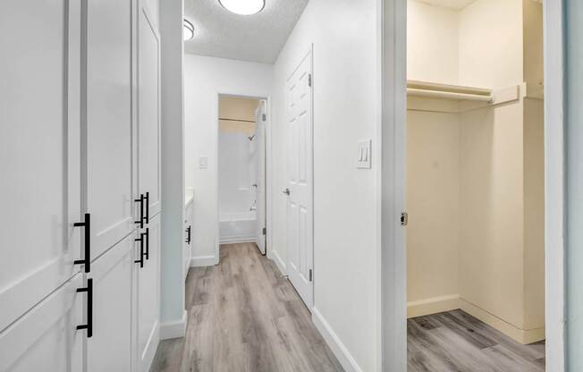 A hallway with white cabinets and a light brown floor.