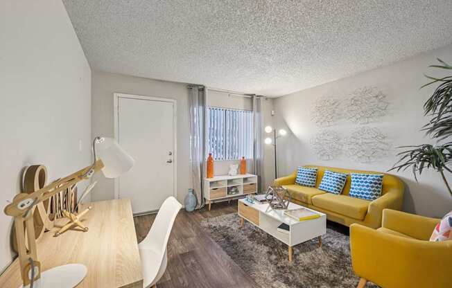 A living room with a yellow couch and a white chair.