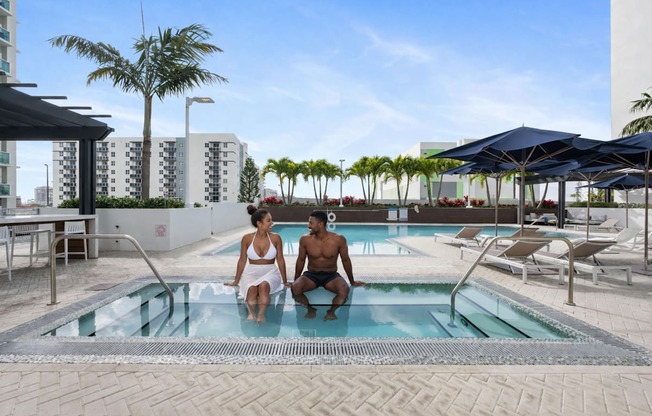 Two people are sitting in a pool on a sunny day.