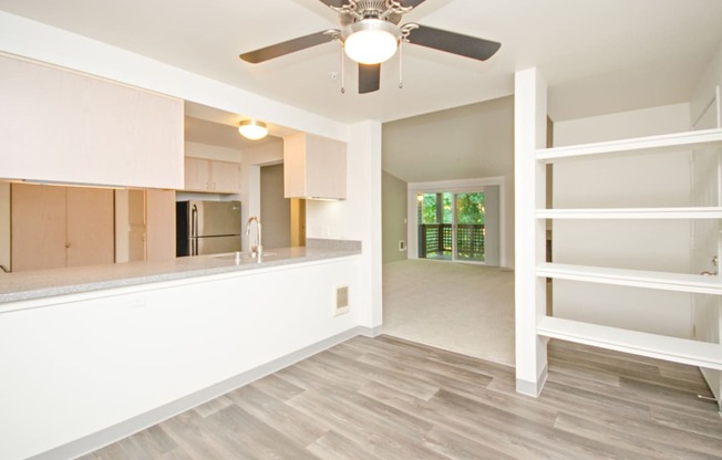 an empty living room and kitchen with a ceiling fan