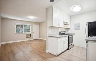 an empty kitchen and living room with white cabinets and appliances