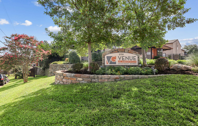 A sign that says "VENUE" is in front of a tree.